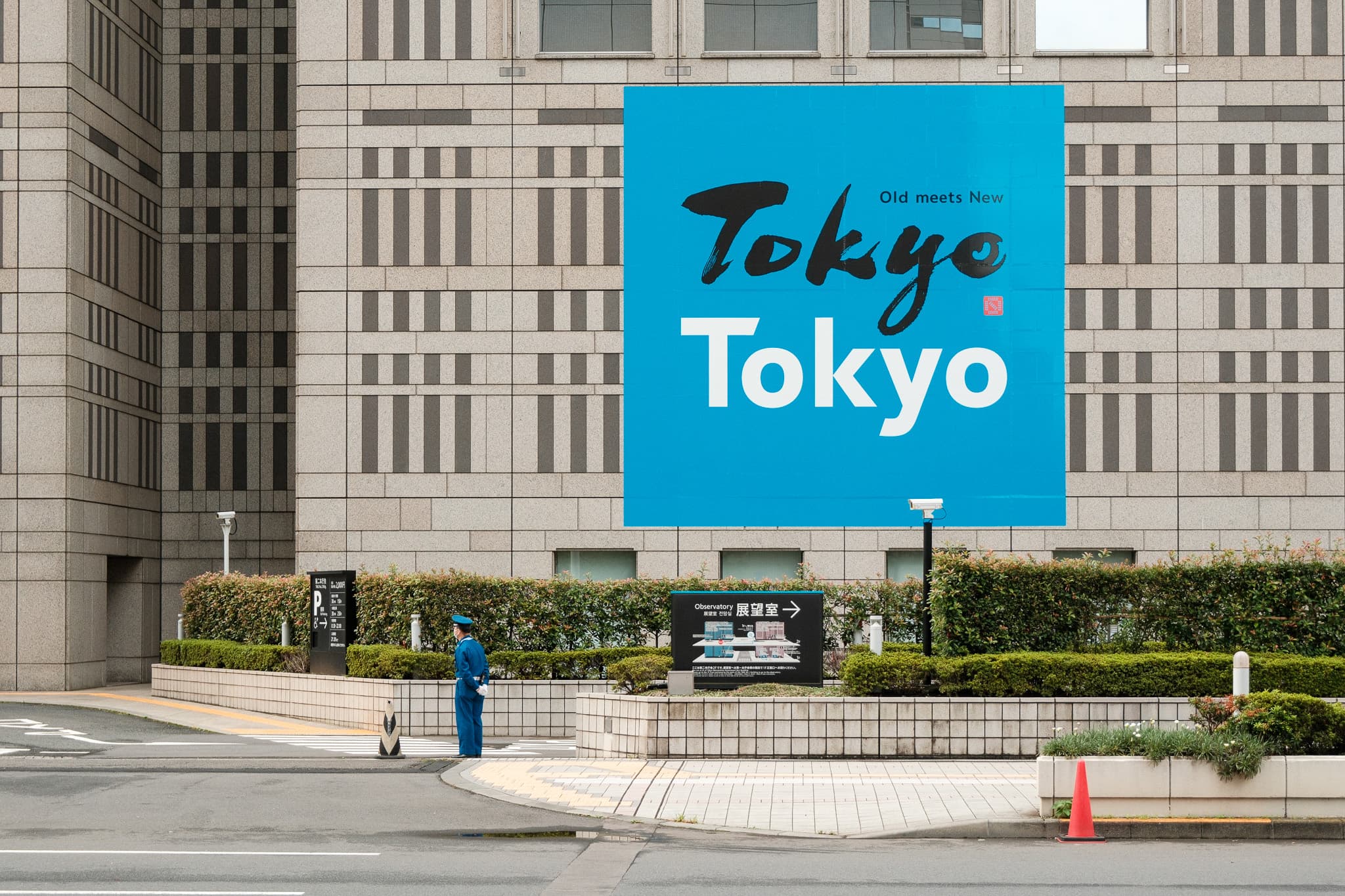 A blue Tokyo sign in front of a tall building