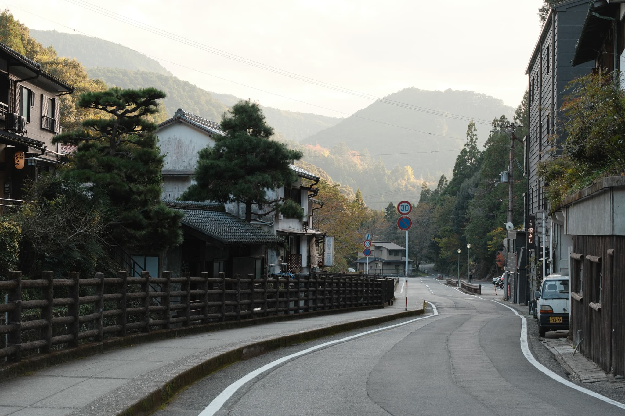 A quiet road between traditional buildings and green mountains