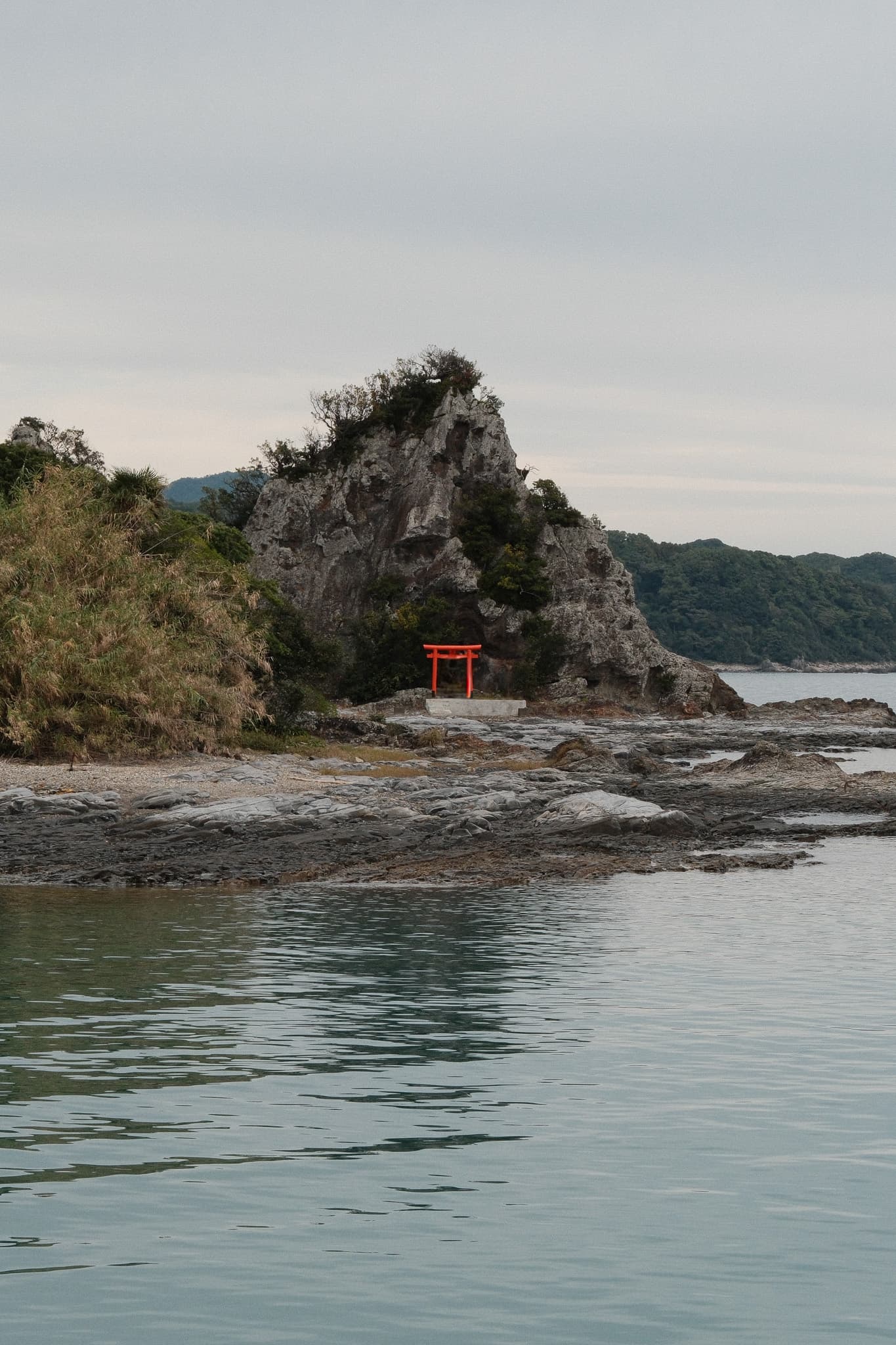 A small shrine on a rocky island beside calm water