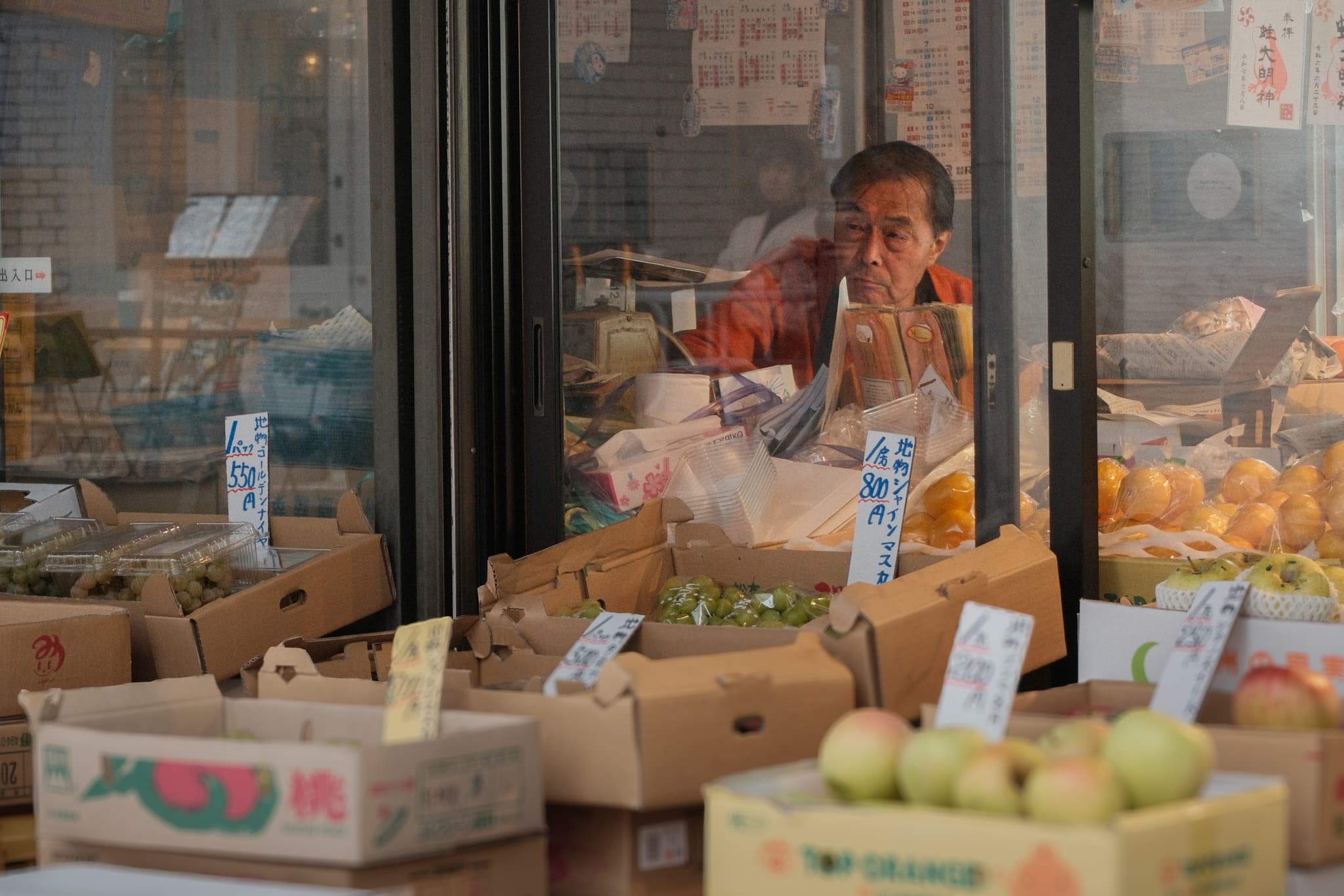 A shopkeeper behind a window filled with produce