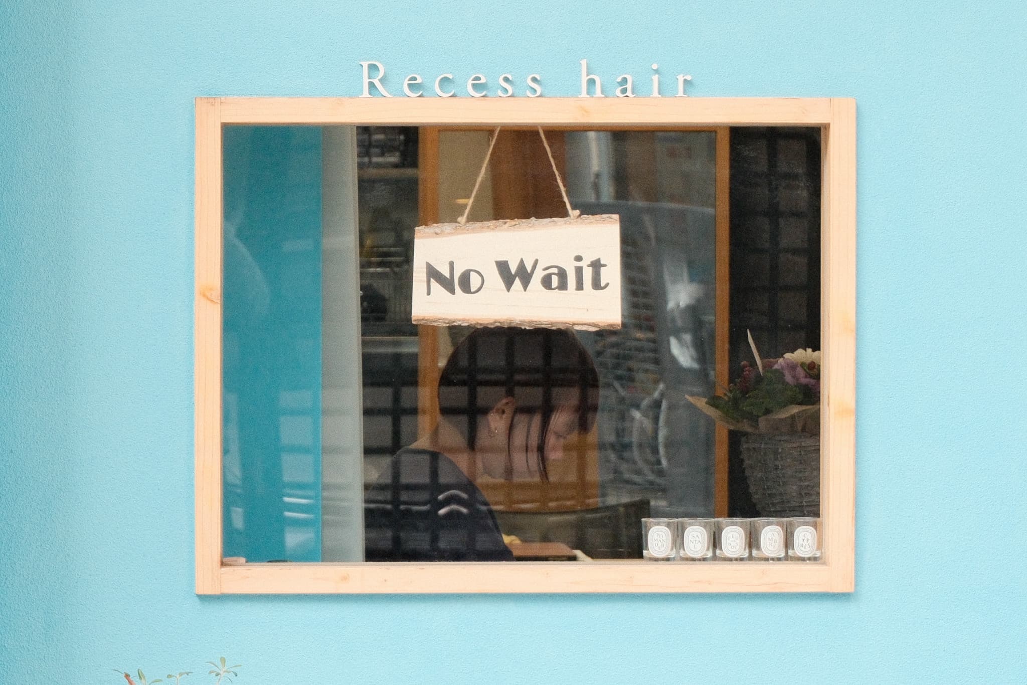 A No Wait sign in the window of a blue hair salon