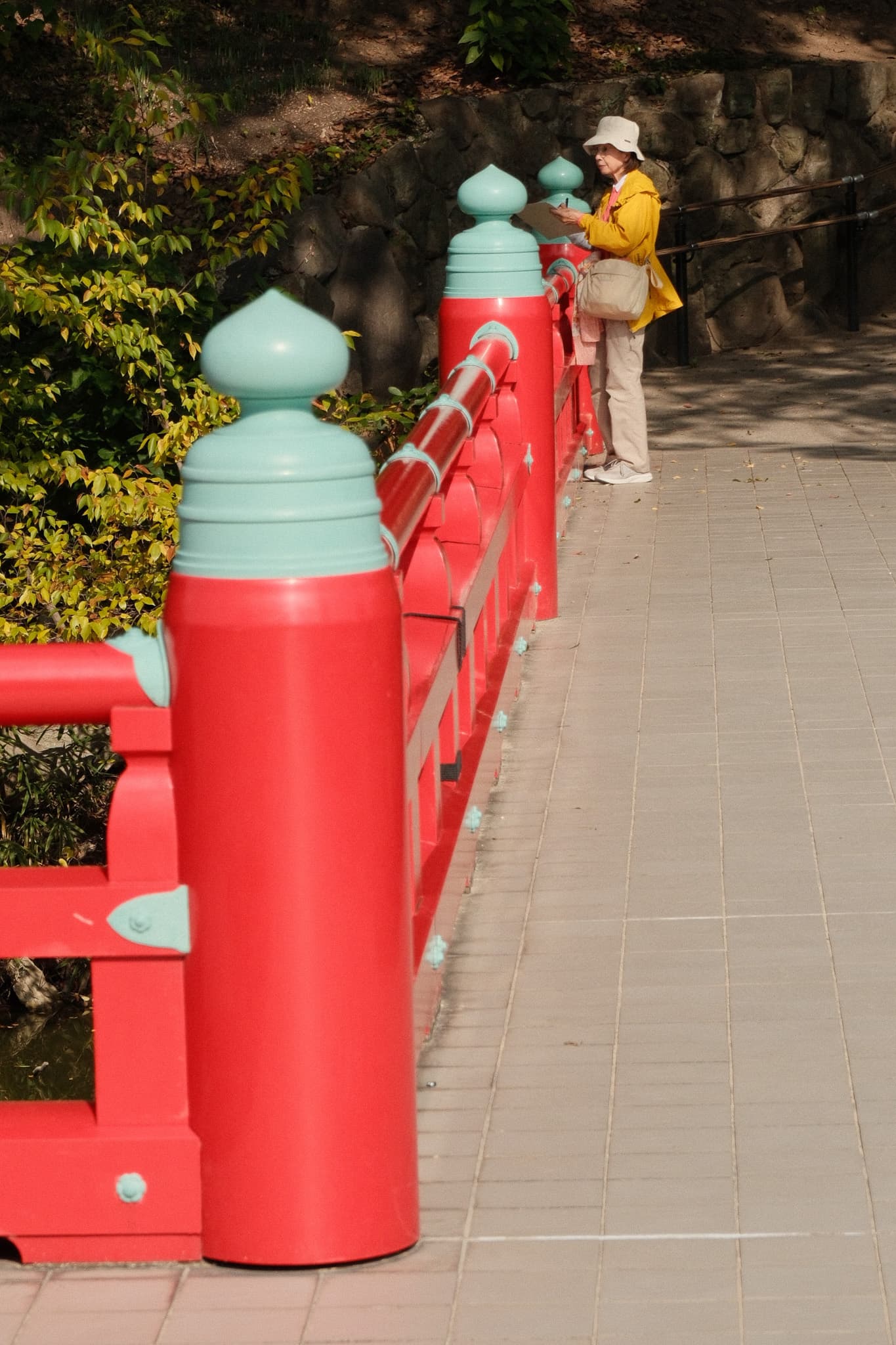 Bright red posts and green finials along a tree-lined path