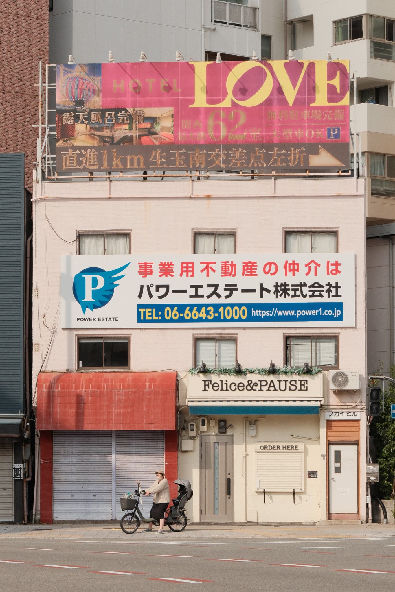 A cyclist passing a building covered in colorful signs